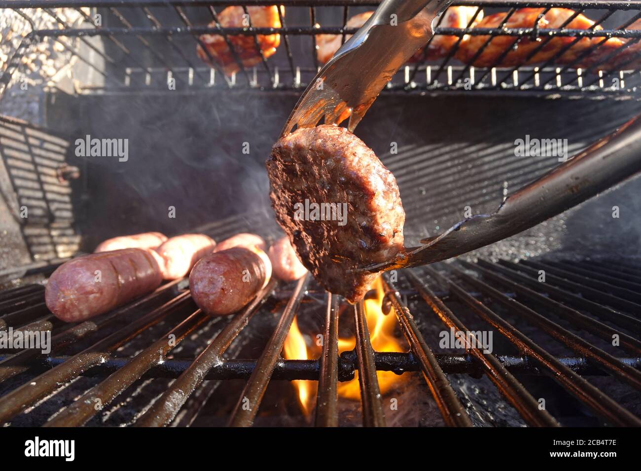 Primo piano di salsicce e hamburger su barbecue a gas Foto Stock