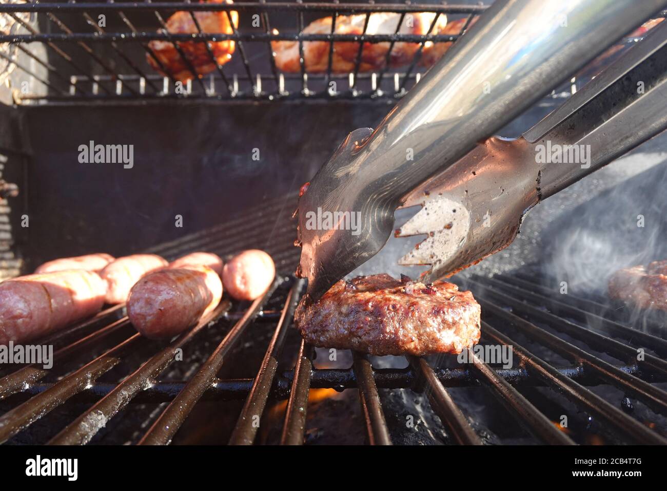 Primo piano di salsicce e hamburger su barbecue a gas Foto Stock