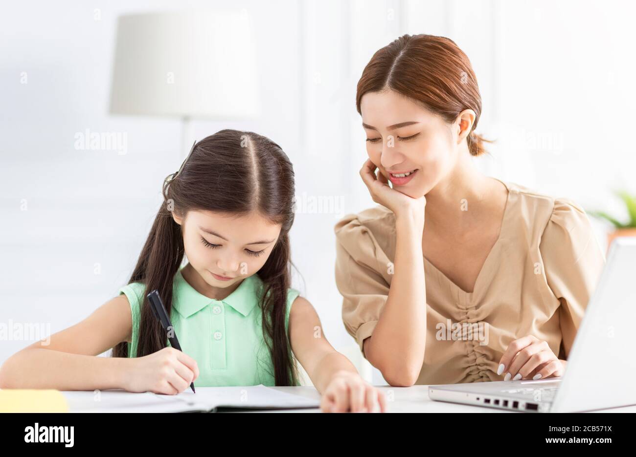 La madre sta lavorando e insegnando la sua figlia che fa il lavoro domestico Foto Stock