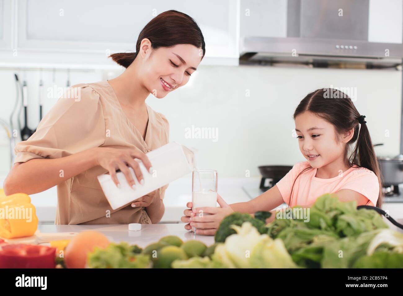 madre e bambino bevono latte in cucina Foto Stock