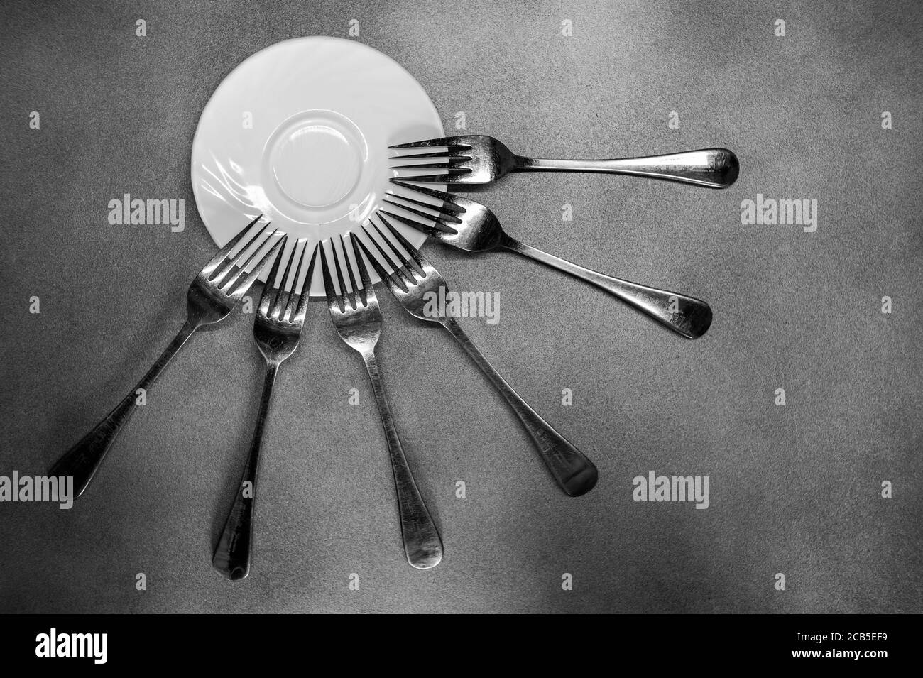 foto delle forche che si sono avulse intorno a una piastra in primo piano su un sfondo grigio Foto Stock