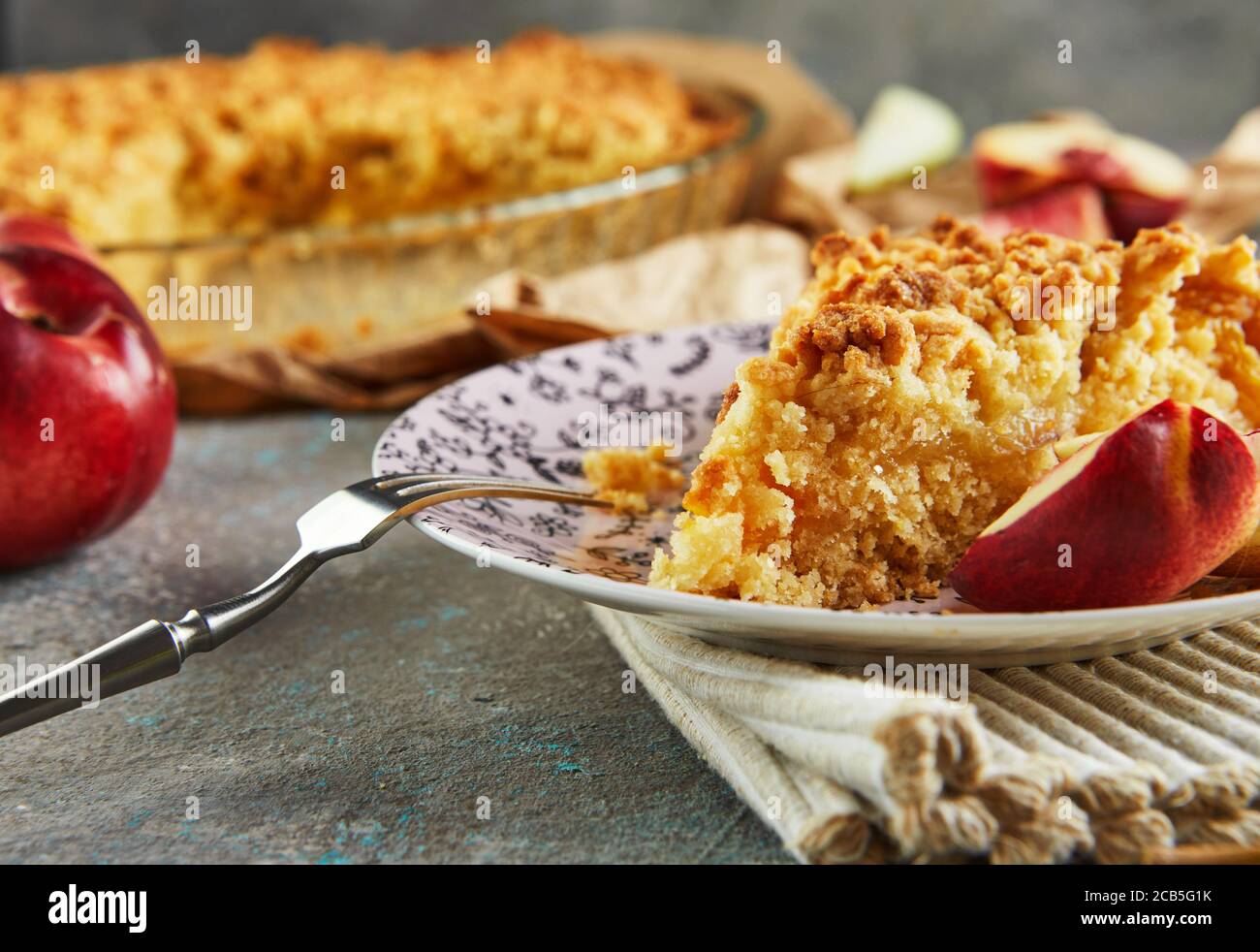Torte fatte in casa, un pezzo di torta su un piatto con pesche e pere su cemento grigio-blu. Primo piano Foto Stock