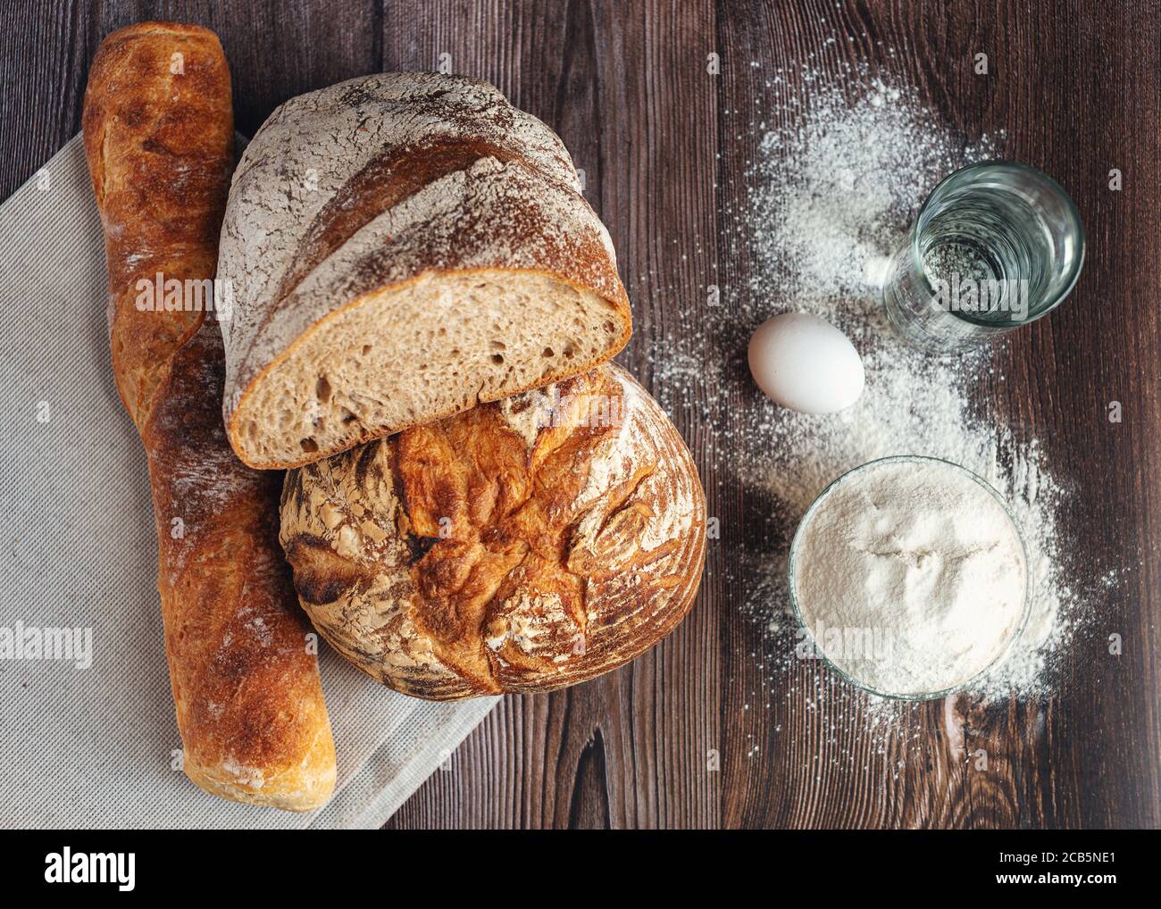 Pane di grano e segala, baguette e farina di grano su tavola di legno Foto Stock
