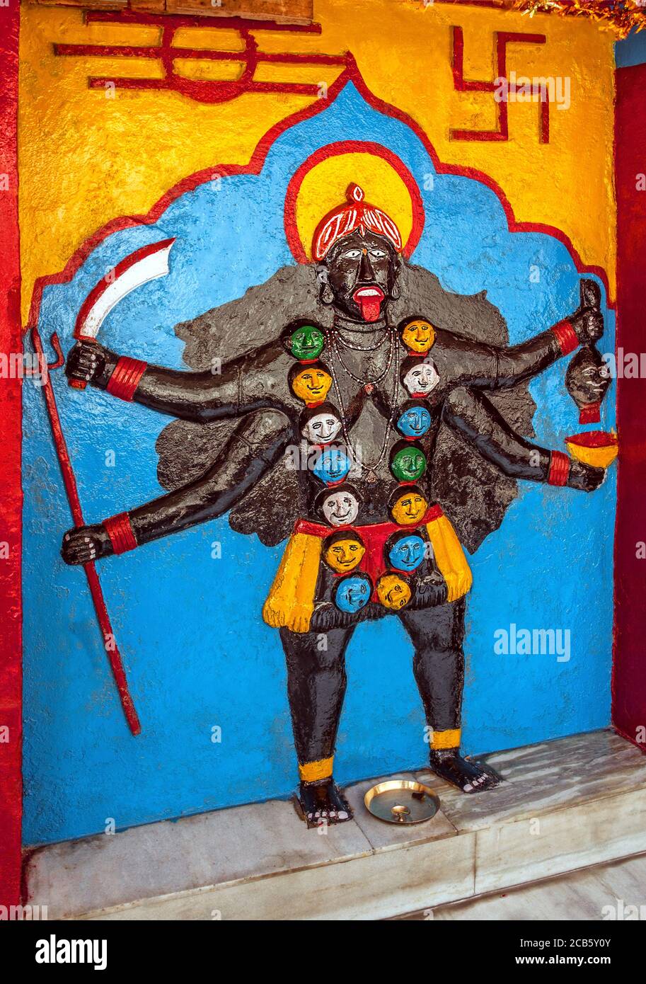 Statua dello Shiva, armato di molti, al muro del tempio con una swastika come simbolo del movimento della vita nella valle di Spiti, India Foto Stock