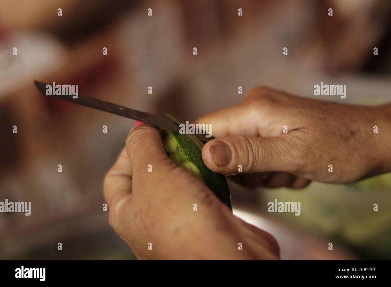 Madre indiana che taglia verdure verdi con coltello tagliente affilato Chiudi su Foto Stock