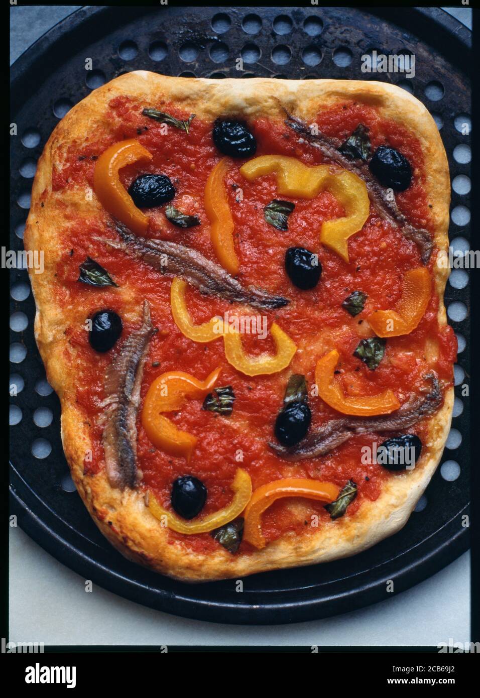 Pizza a base di pomodoro con olive, peperoni, basilico e acciughe Foto Stock