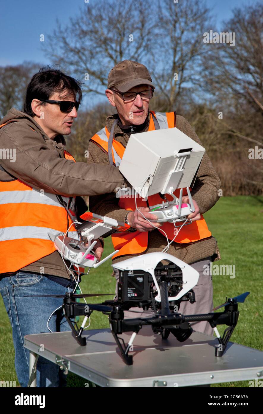 Due fotografi si preparano a volare un drone con una macchina fotografica In un giardino di Cotsold Foto Stock