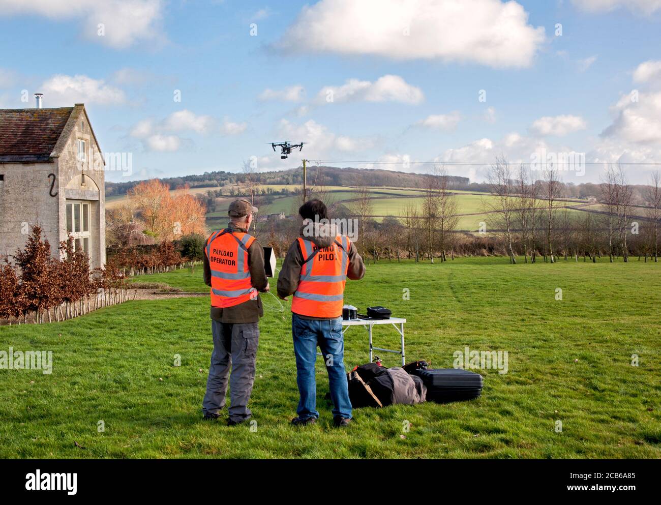 Due fotografi che volano un drone con una fotocamera in un Ampio giardino di campagna nel Cotswolds Foto Stock