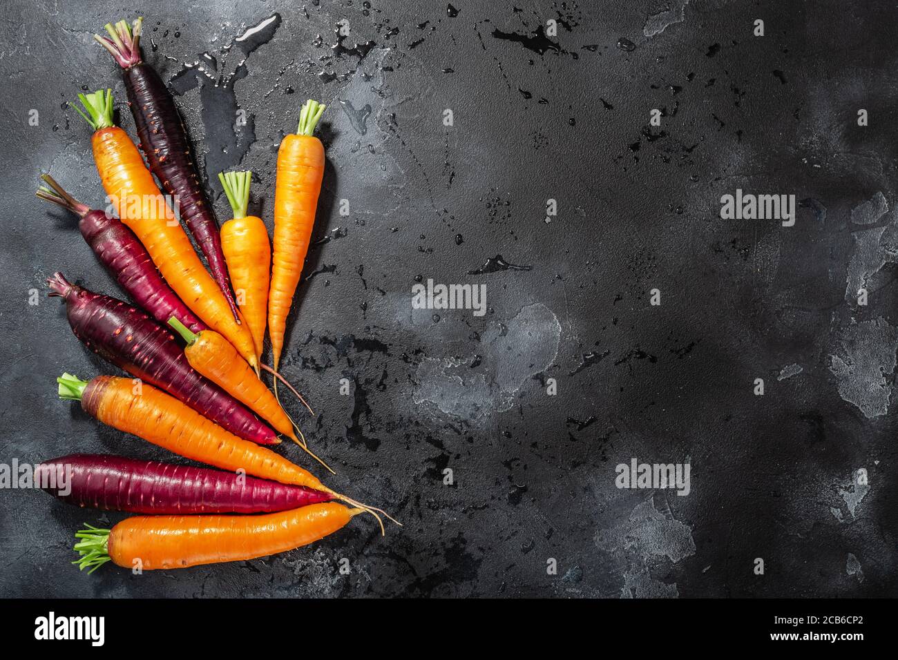 Carote, arancione e viola antocianina-ricco su sfondo di cemento lavato con spazio di copia, vista dall'alto Foto Stock