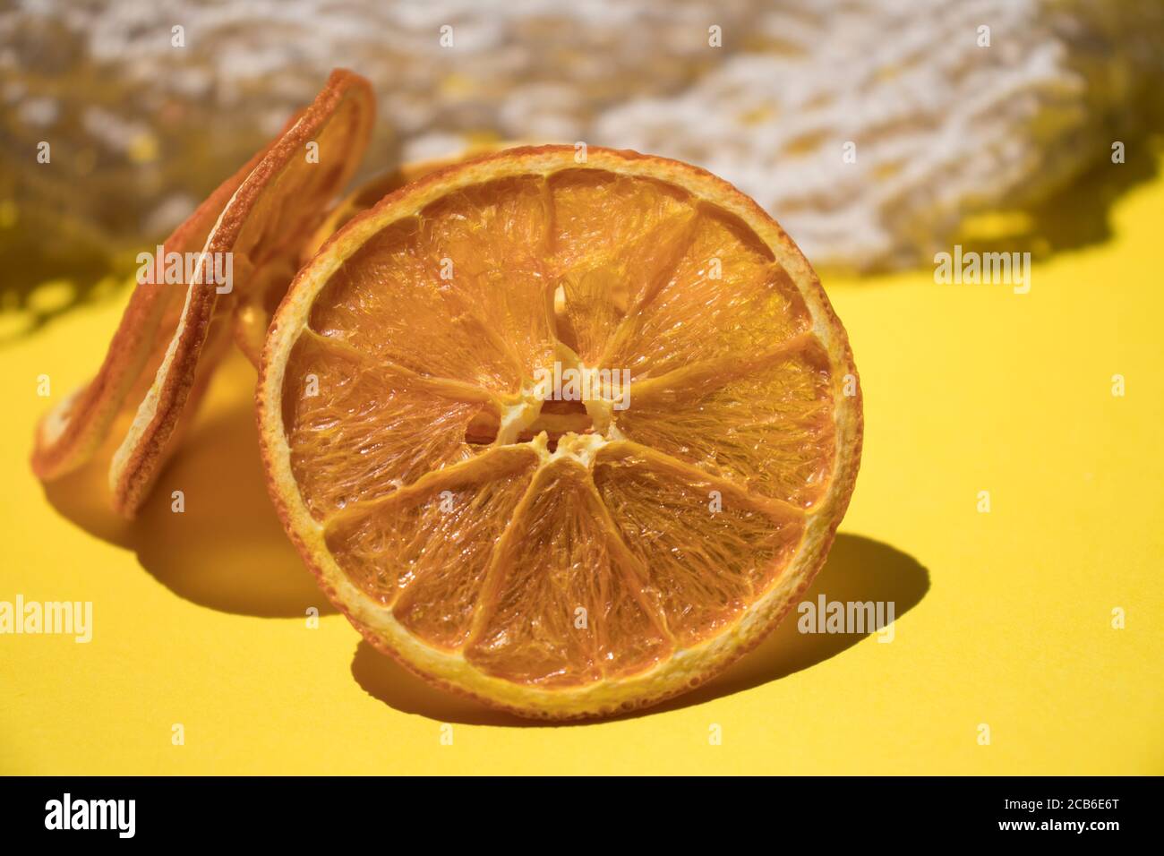 Preparazione a casa. Arancia secca a fette, patatine di frutta naturali senza zucchero e spezie su sfondo giallo. Foto Stock