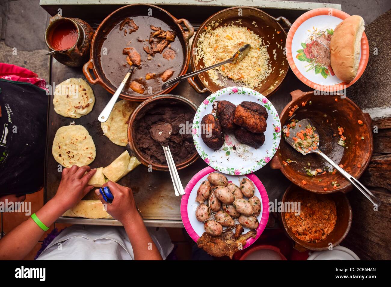 Donna irriconoscibile mani che cucinano sopra contatore pieno di cibi tradizionali guatemaltechi, Guatemala Foto Stock
