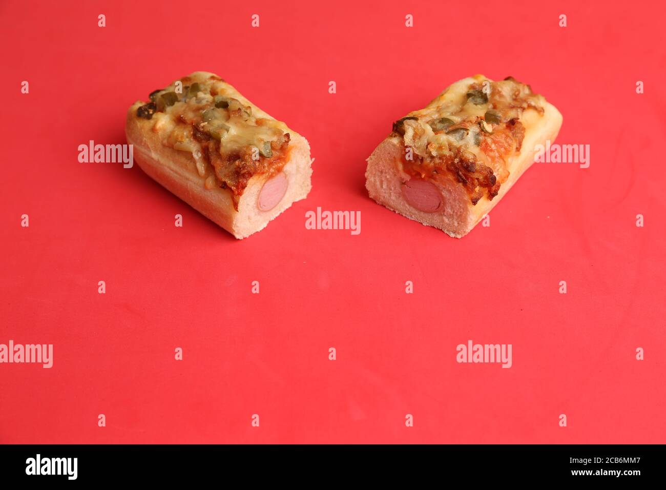 Primo piano di due pezzi di loafs di pizza con salsiccia su sfondo rosso Foto Stock