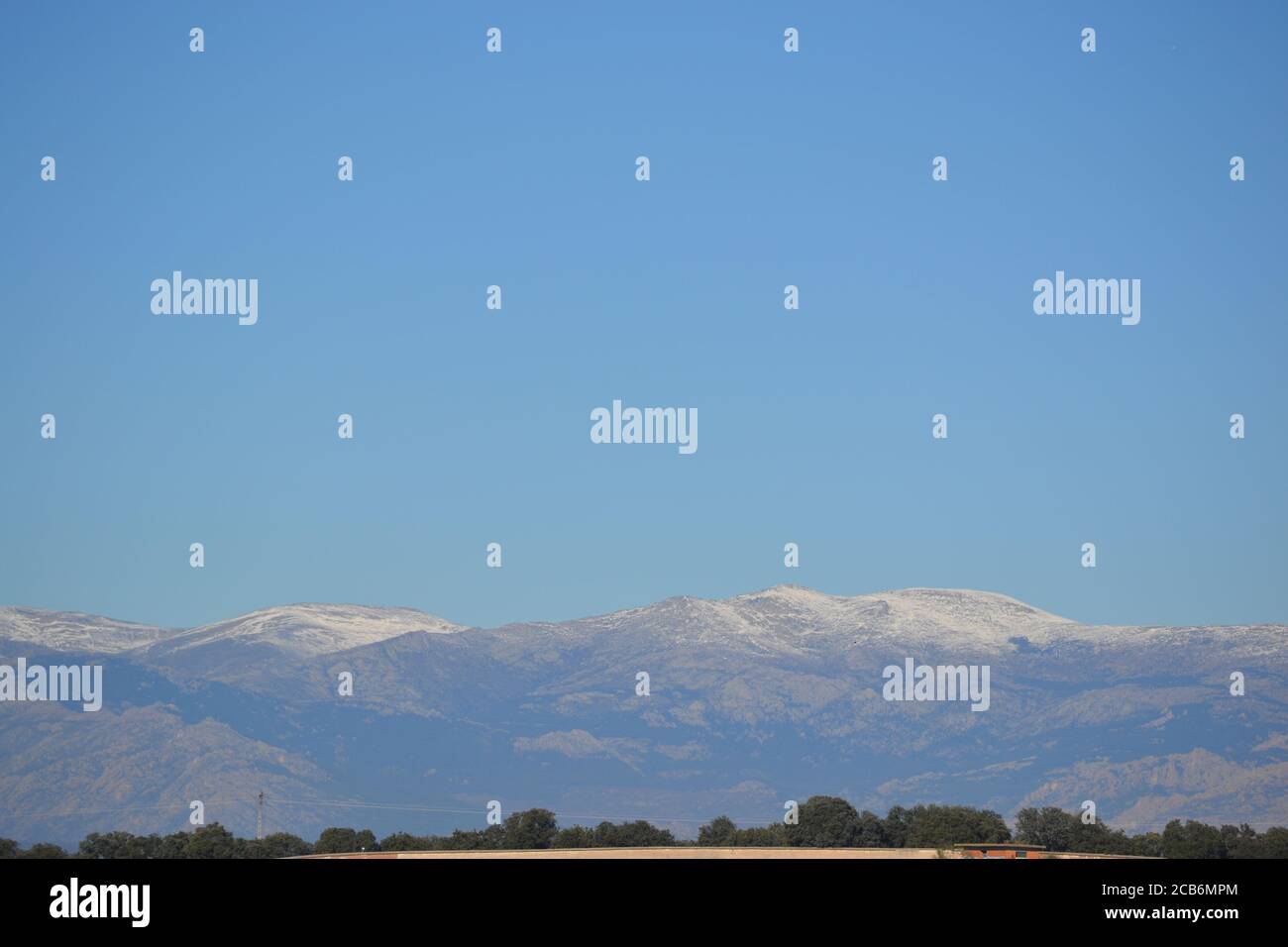 La Sierra de Madrid con neve in cima e un campo asciutto, in Spagna. Foto Stock