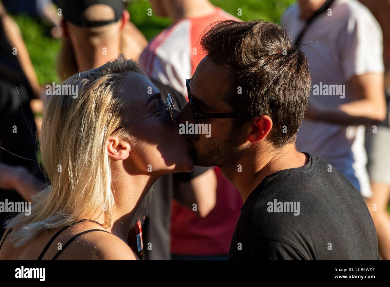 Giovane coppia baciando in una folla Foto Stock