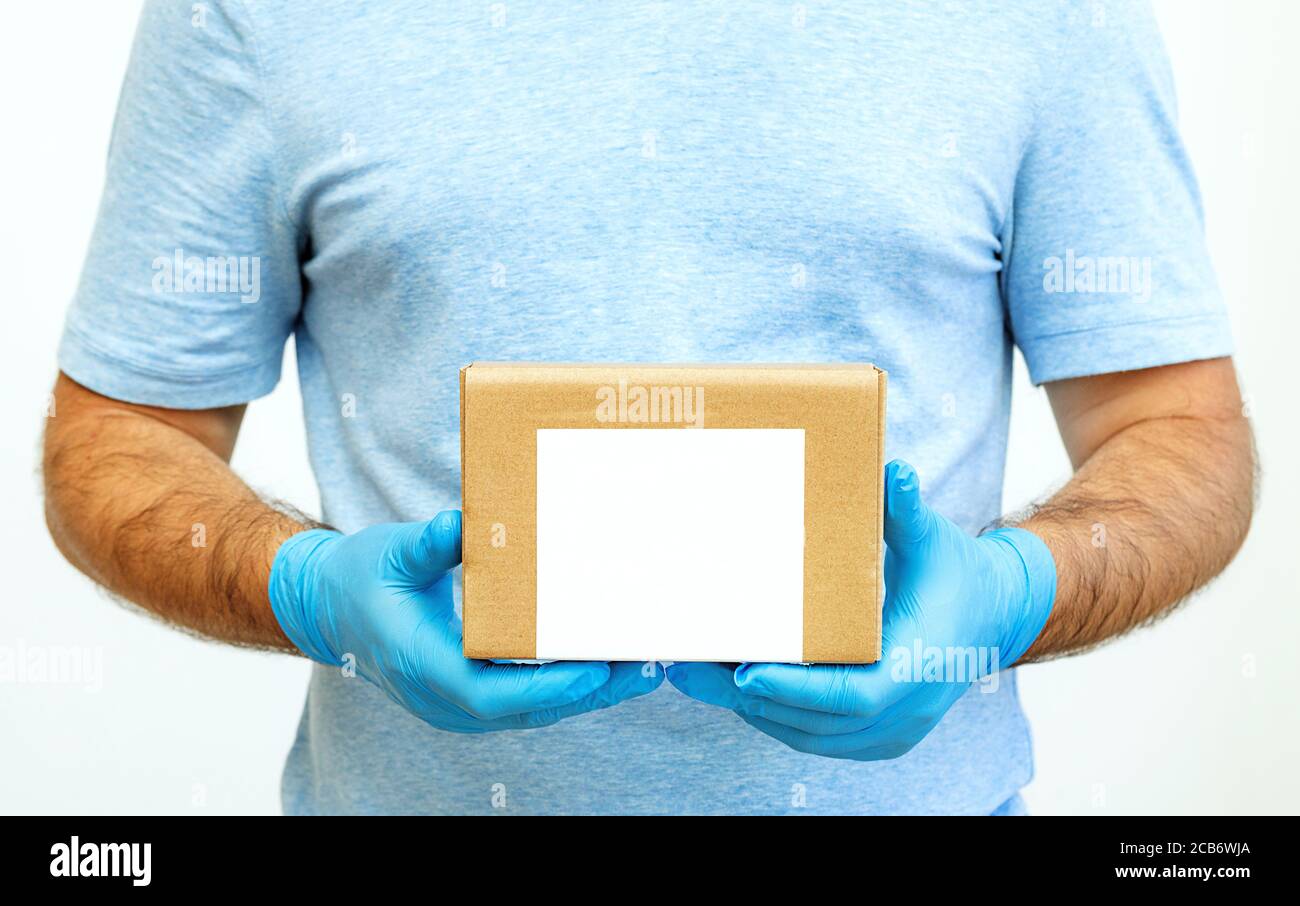 Le mani del corriere in guanti di gomma medica che tengono scatole di cartone. Consegna porta. Servizio di consegna. Quarantena. Foto Stock