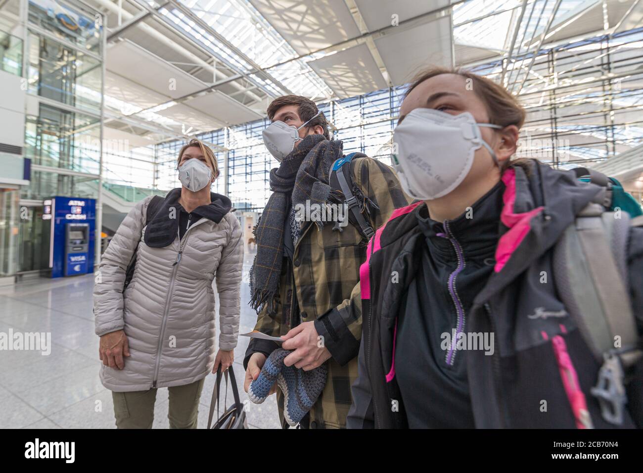 Familly all'aeroporto di Monaco con mascherine protettive alla ricerca voli Foto Stock