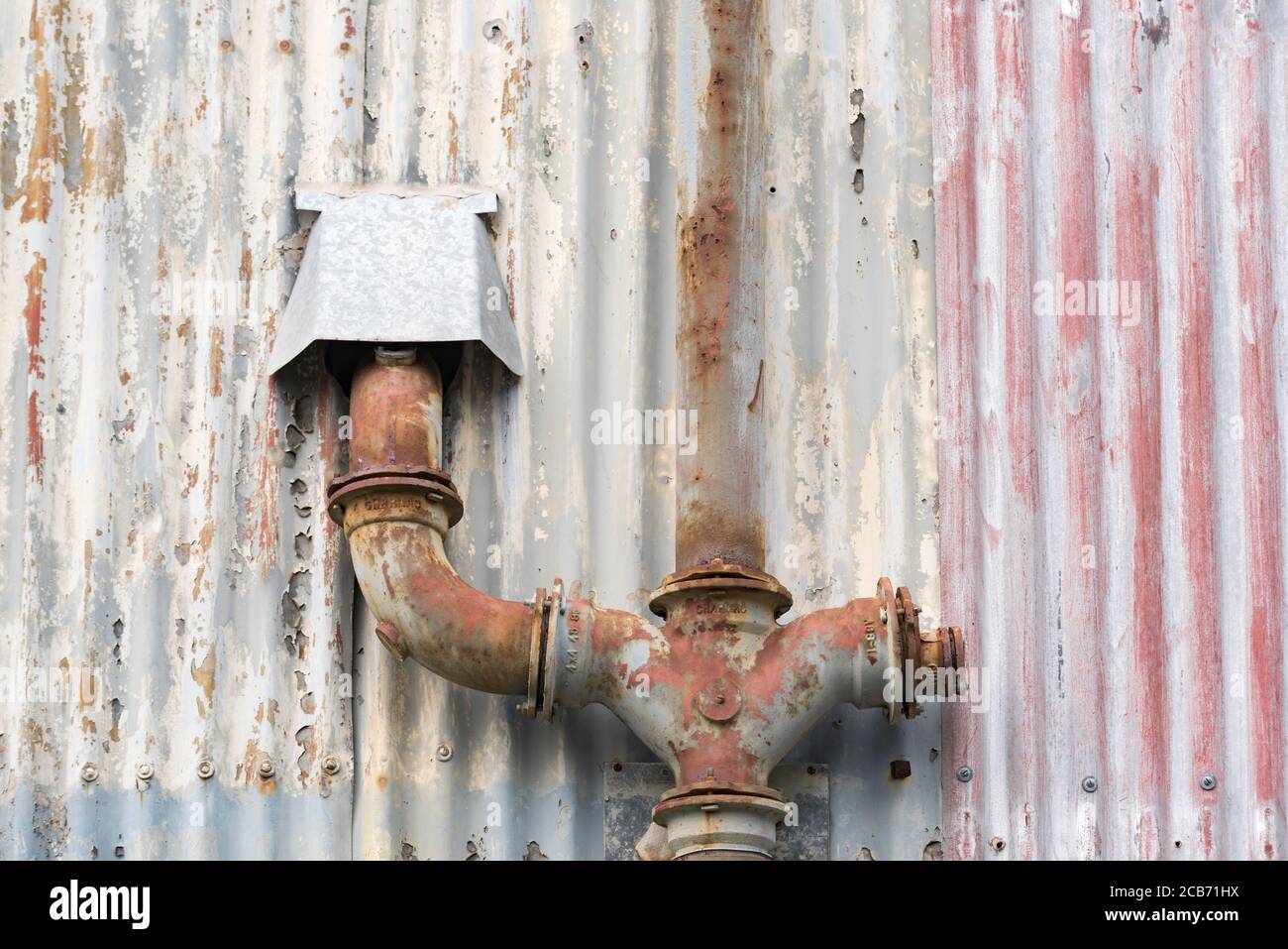 Sbucciatura e scoloritura su un vecchio ferro ondulato parete con linee verticali parallele Foto Stock