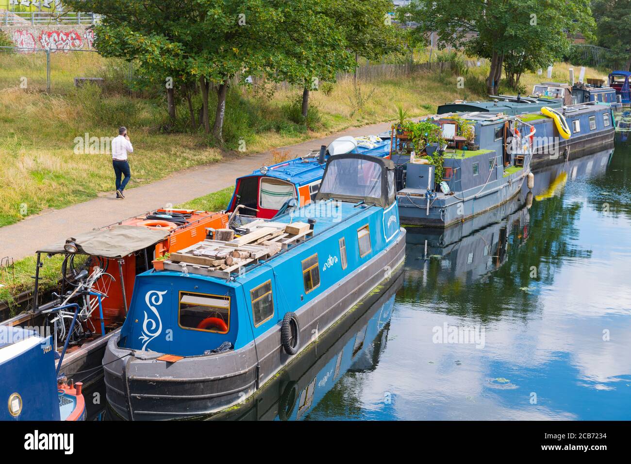 Inghilterra Londra Stratford Park Hackney Wick alzaia chiatte case galleggianti acqua Fiume Lee Lea riflessione acqua uomo cella a piedi Foto Stock