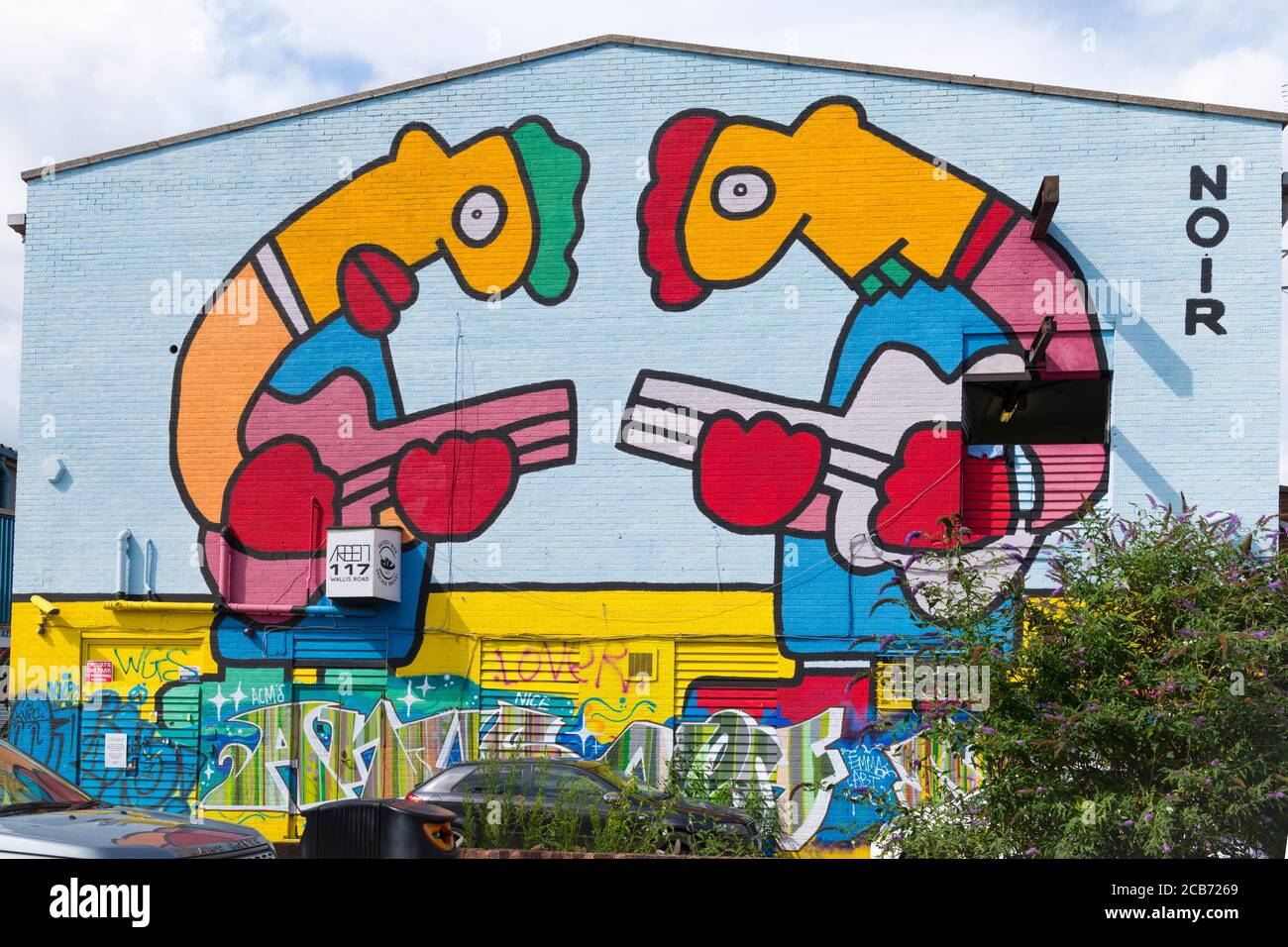 Inghilterra Londra Stratford Park Hackney Wick graffiti Noir due giganti figure che suonano chitarre muro di mattoni capannone magazzino Foto Stock