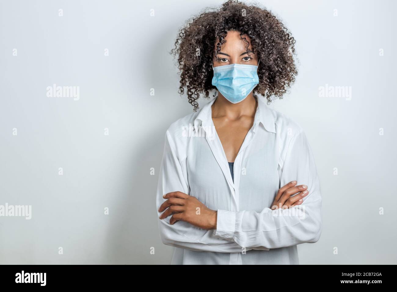 ritratto di una donna afro con maschera chirurgica e attraversato mani Foto Stock