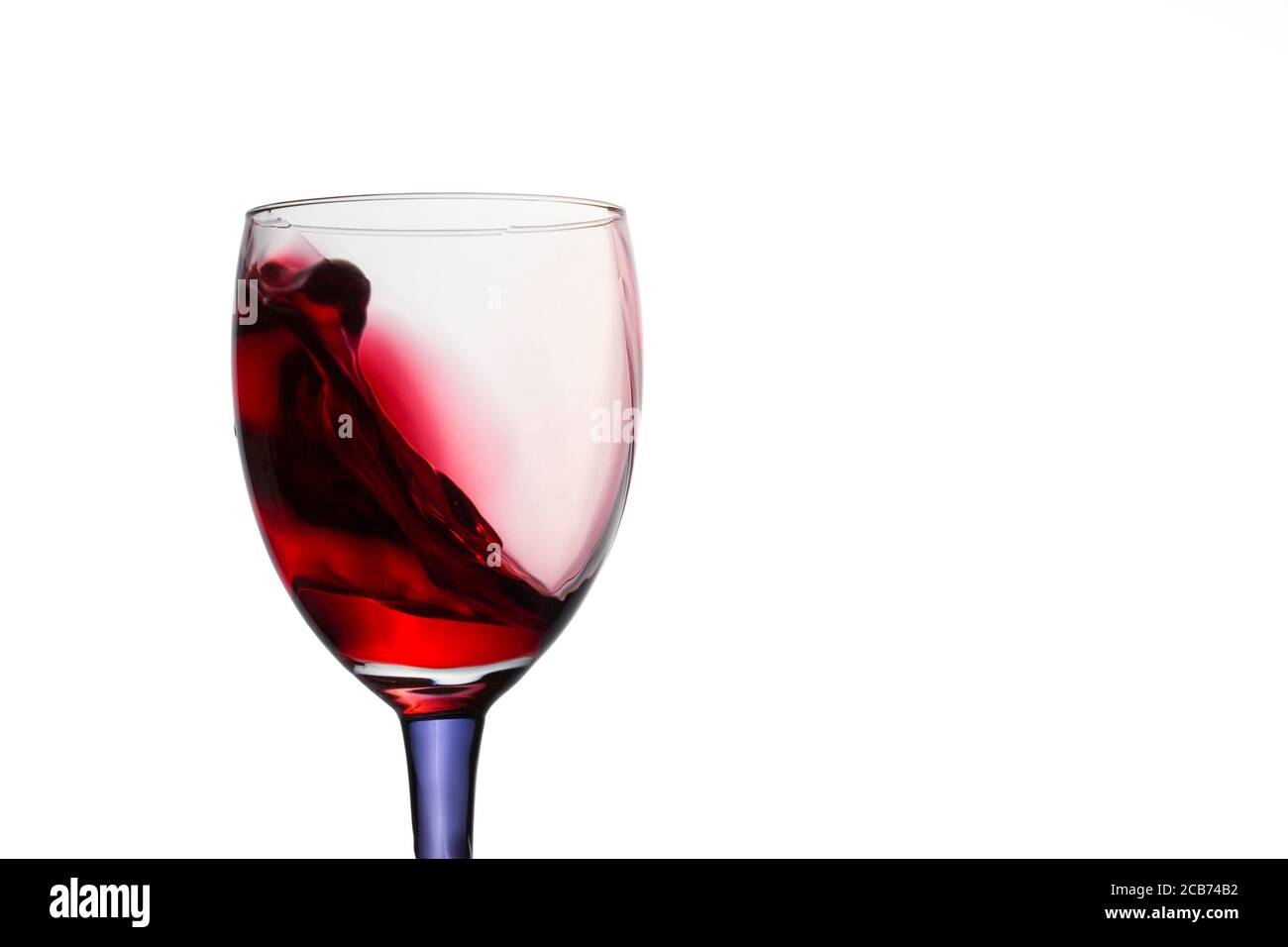 un tuffo di vino rosso simile a un'onda di mare un vetro trasparente su sfondo bianco luminoso e bello concetto di bevanda alcolica Foto Stock