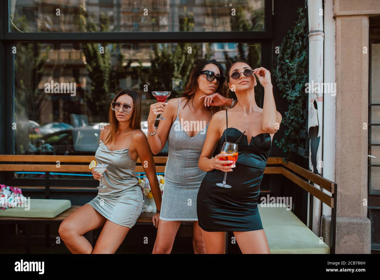 Tre belle donne caucasiche in abiti corti e stretti sono bere cocktail in  un bar-giardino. Ragazze e festa Foto stock - Alamy