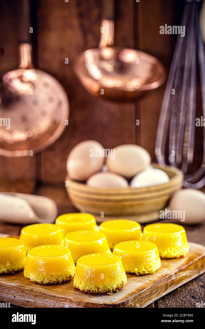 Caramella di tuorlo d'uovo, chiamata Quindim in Brasile, e Portogallo in brisa-do-Lis. Dolce dessert su rustico sfondo di legno Foto Stock