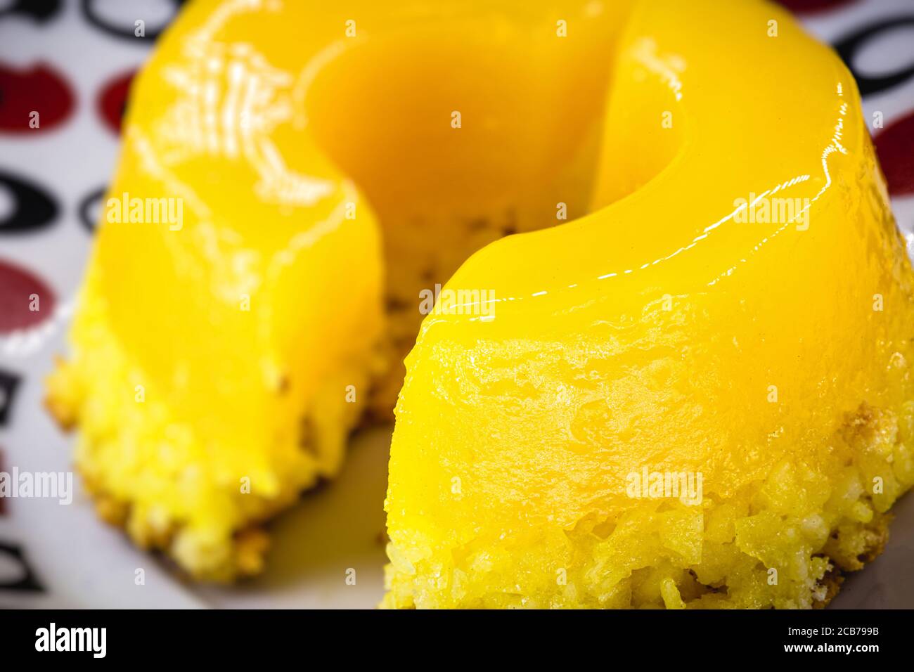Pezzo di Quindim, piccolo budino tagliato da uovo brasiliano, con zucchero e cocco grattugiato. Foto macro o closeup della cucina brasiliana Foto Stock