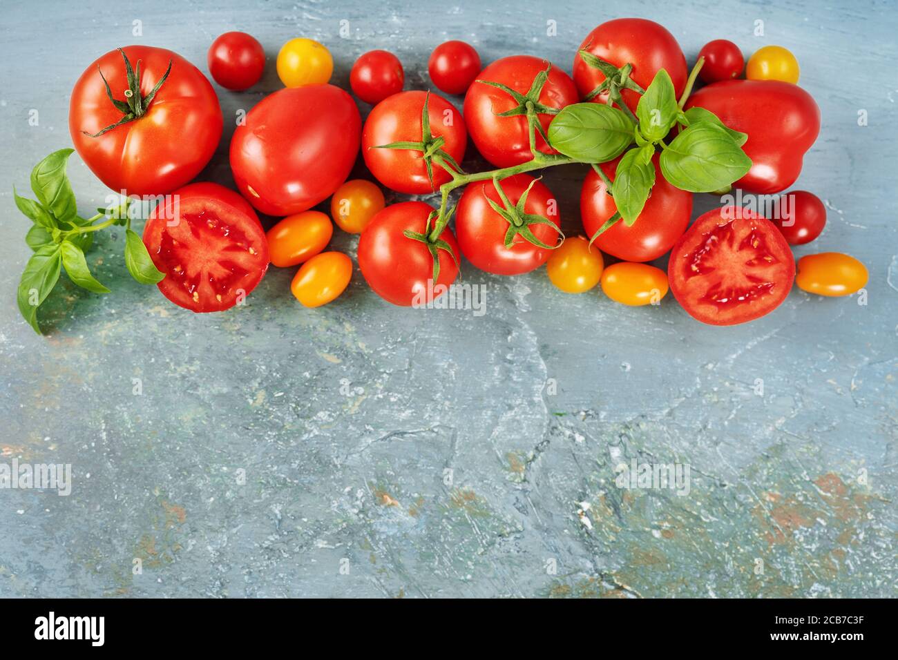 Vista dall'alto di molti pomodori rossi freschi e succosi sul parte superiore dell'immagine su sfondo blu Foto Stock