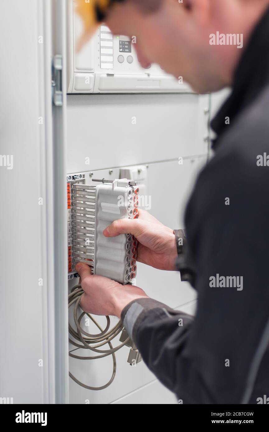 Il tecnico dell'elettricista verifica gli impianti elettrici e i fili sul sistema di protezione relè. Unità di controllo vano. Gruppo di comando a media tensione Foto Stock