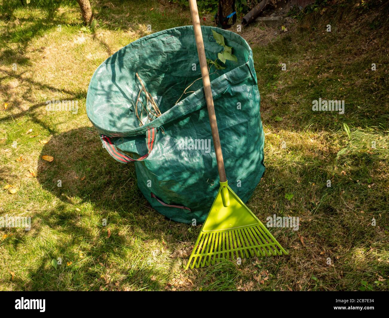 Rastrelli a foglia e contenitori di rifiuti verdi nel giardino Foto Stock