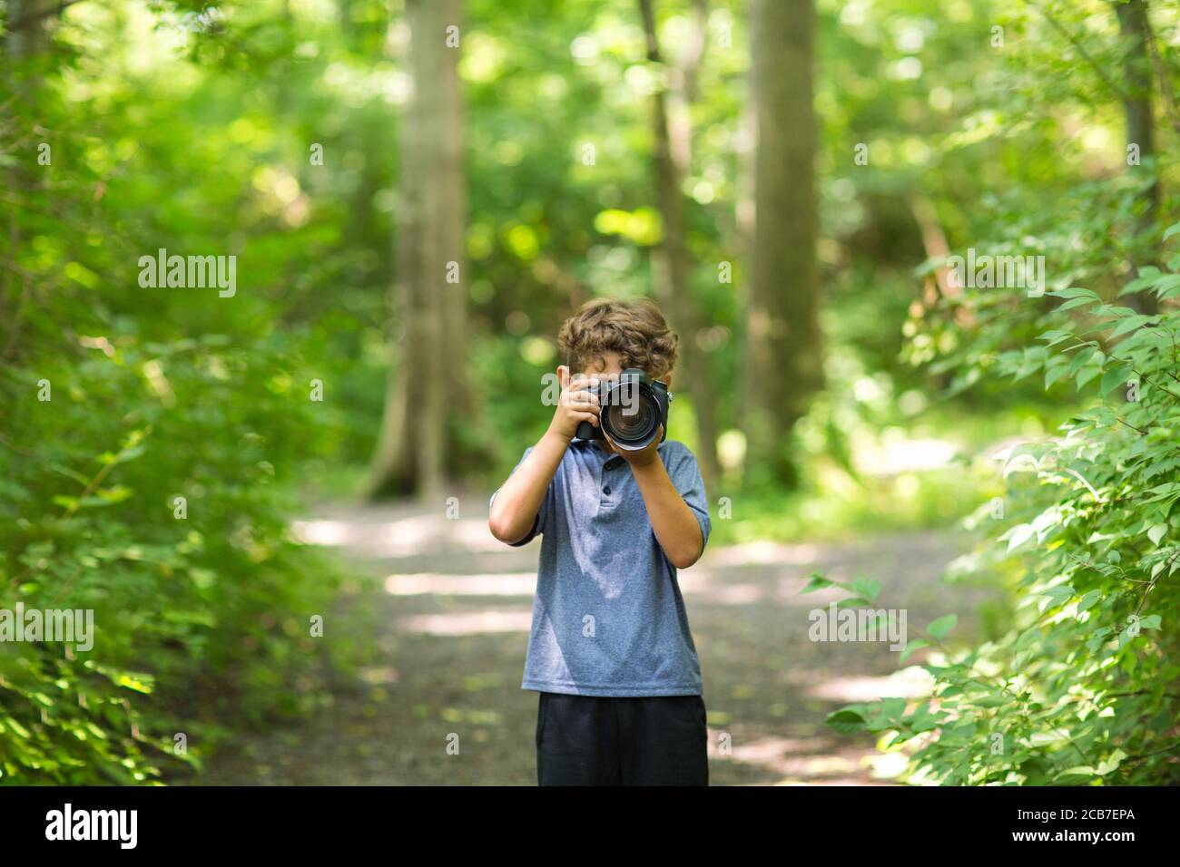 Ragazzo giovane che scatta una foto nella foresta. Foto Stock