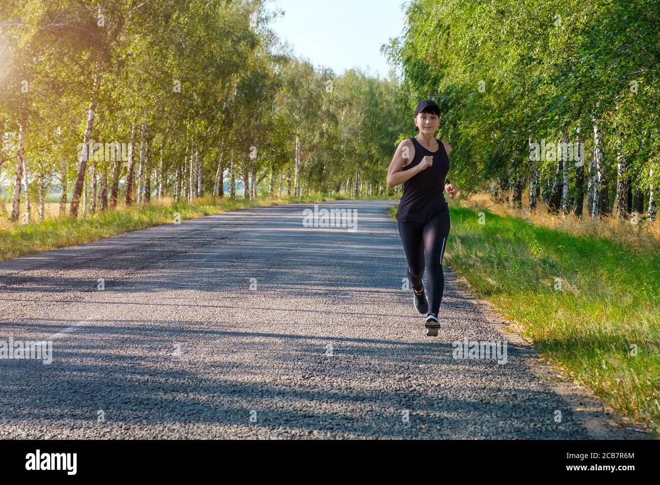 giovane donna bianca forma fisica corre lungo paese lato strada, vista frontale. Foto Stock