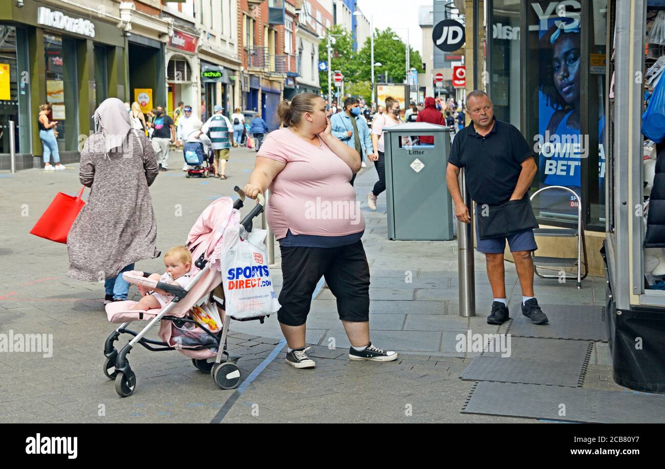 Signora molto grassa, l'acquisto di maschere viso dal venditore di strada Foto Stock