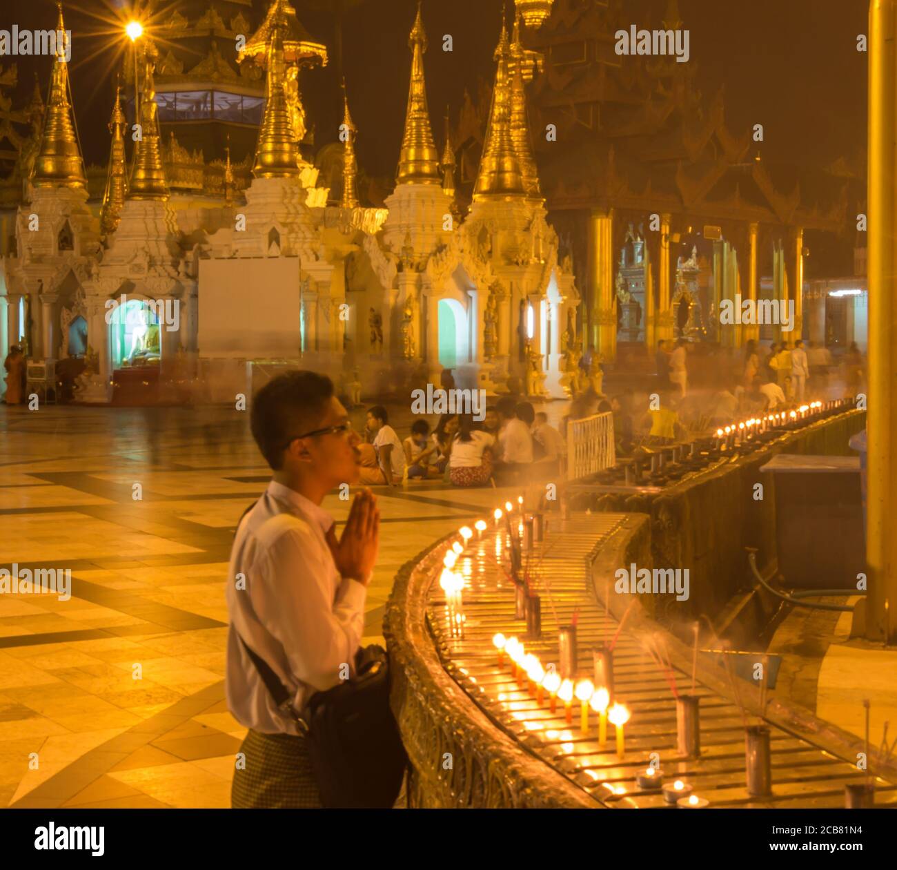 Yangon, Myanmar - 18 dicembre 2017: Un uomo che prega accanto ad alcune candele allo Shwedagon Pago di Yangon, Myanmar Foto Stock