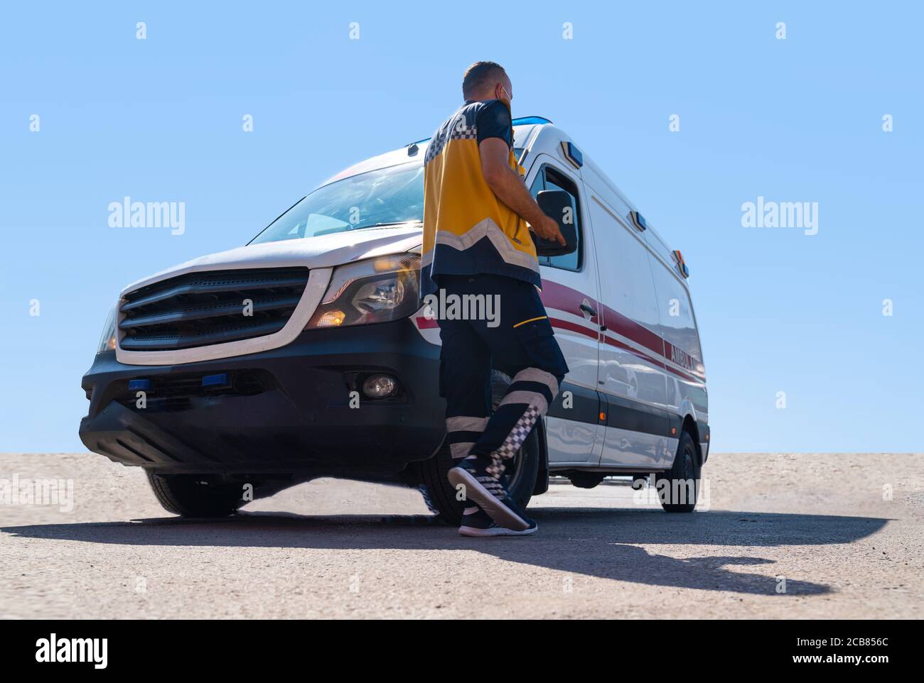 Vista posteriore (posteriore) del professionista della salute va all'ambulanza bianca sotto i raggi solari. Foto Stock