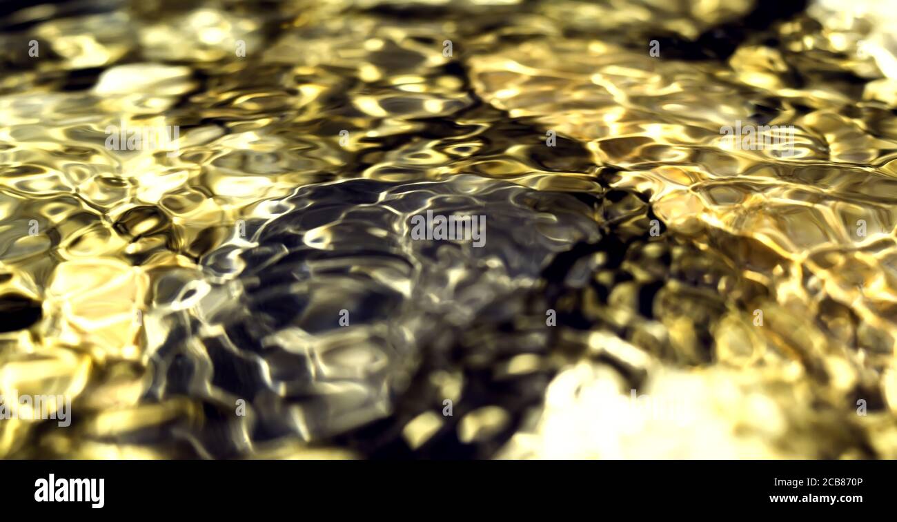 Riflessi dorati sulla superficie dell'acqua, oro liscio e sfondo scuro con motivi circolari. Immagine di sfondo perfetta. Pietre sullo sfondo Foto Stock