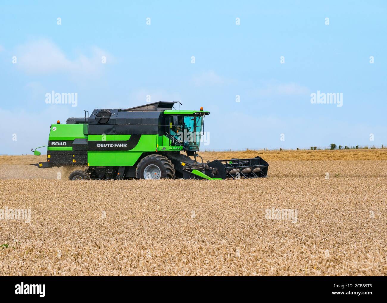 Mietitrebbia Deutz-Fahr per la raccolta di campi di grano in estate Sunshine, East Lothian, Scozia, Regno Unito Foto Stock
