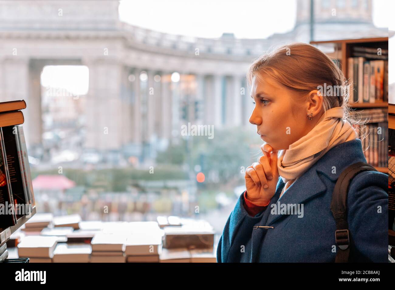 donna sceglie un libro in un negozio. Vista laterale. Il concetto di acquistare libri e di prepararsi per la scuola. Foto Stock