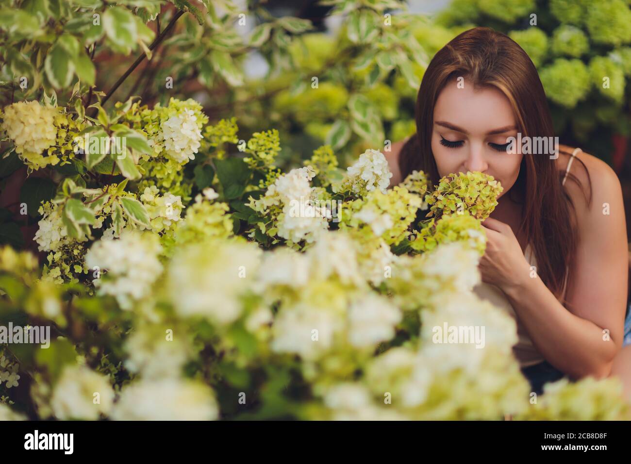 Una ragazza con i capelli blu sniffa i fiori in fiore nel giardino in primavera. Foto Stock
