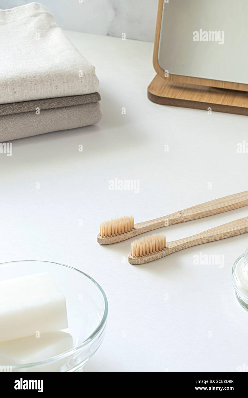 Concetto di zero sprechi. Set di accessori da bagno ecologici - spazzolini da denti in bambù, boccioli di cotone, spazzola per capelli naturali, specchio e nappine di lino. Stile di vita sostenibile. Foto Stock
