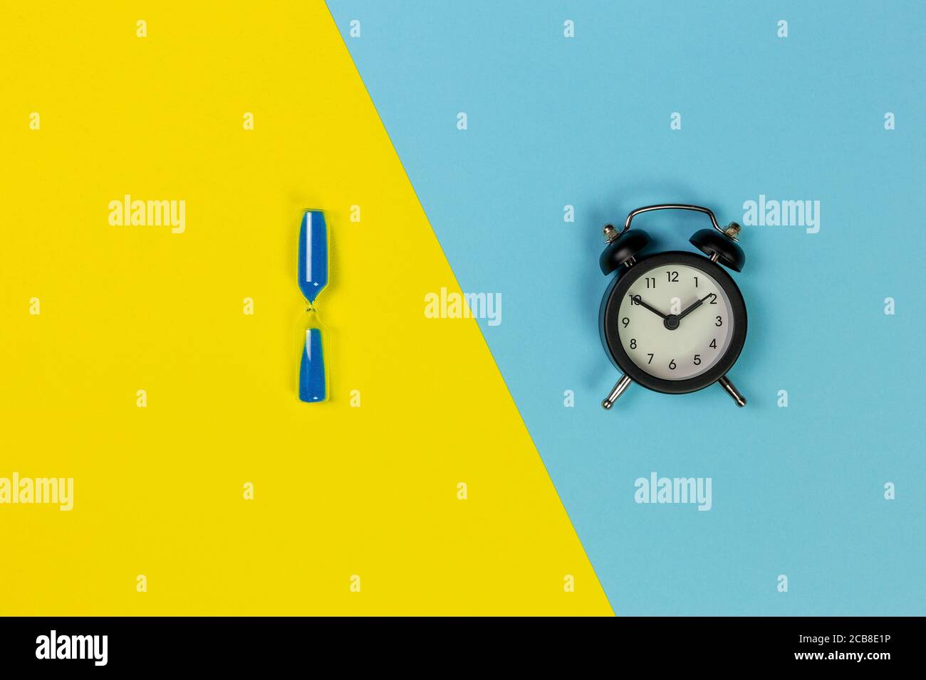 clessidra con sabbia blu e orologio nero su due tonalità sfondo Foto Stock