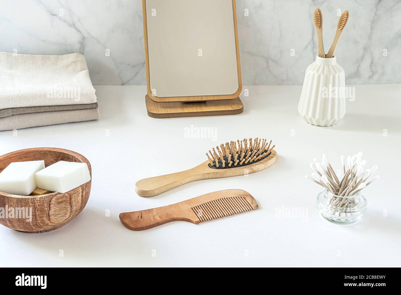 Concetto di zero sprechi. Set di accessori da bagno ecologici - spazzolini da denti in bambù, boccioli di cotone, spazzola per capelli naturali, specchio e nappine di lino. Stile di vita sostenibile. Foto Stock