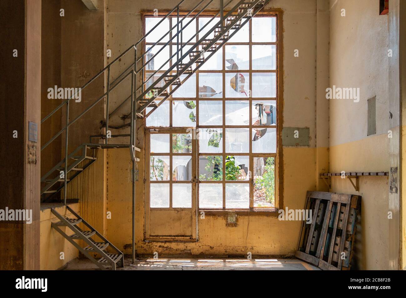 Vecchie finestre rotte, con scale in metallo all'interno di un edificio giallo. Spazio abbandonato Foto Stock