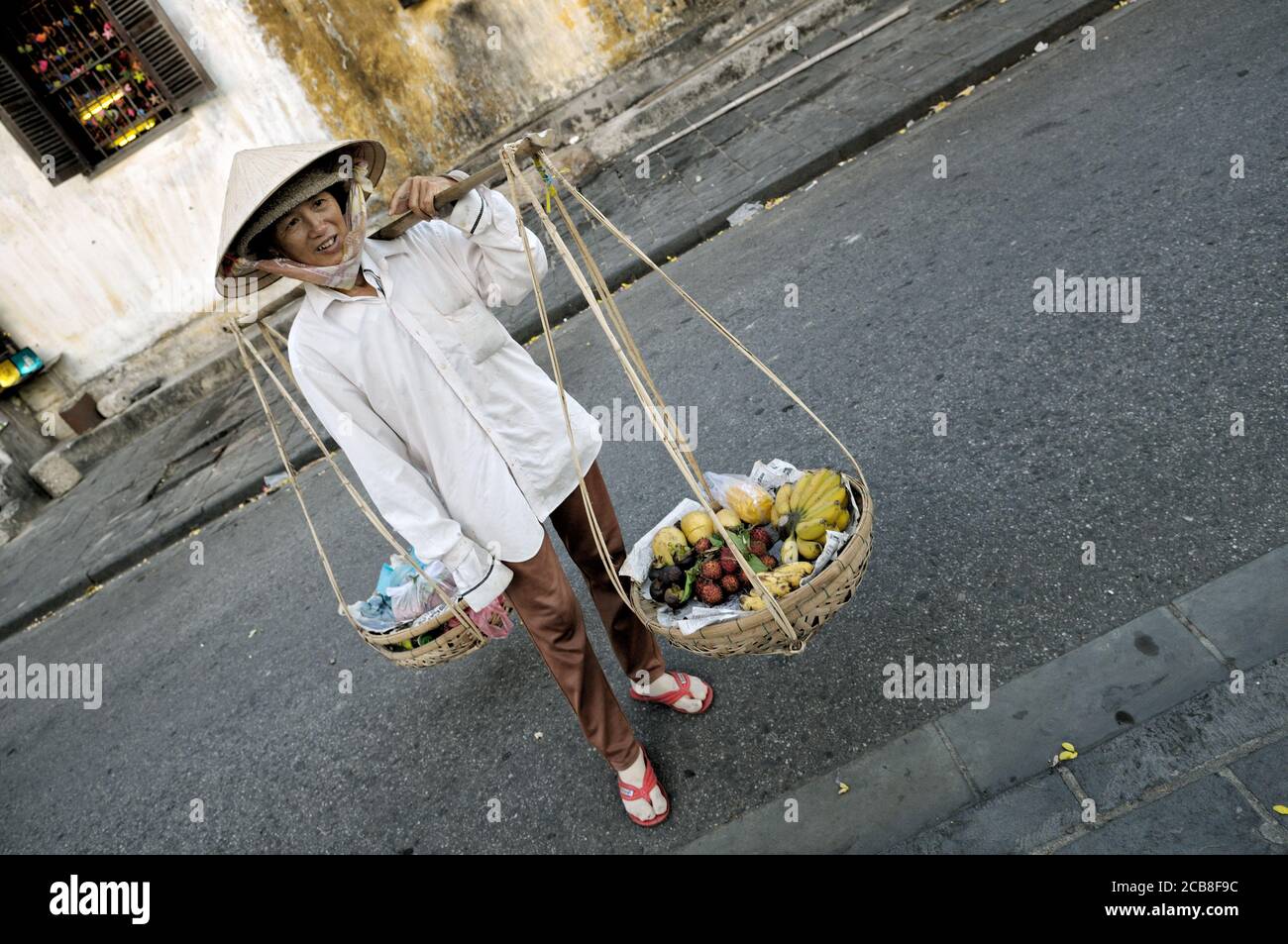 Donna che porta cesti di frutta a Hoi An, Vietnam Foto Stock