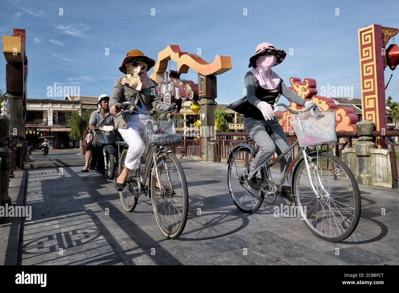 Donne con maschere facciali su un ponte Hoi An (Ponte delle luci), Vietnam Foto Stock
