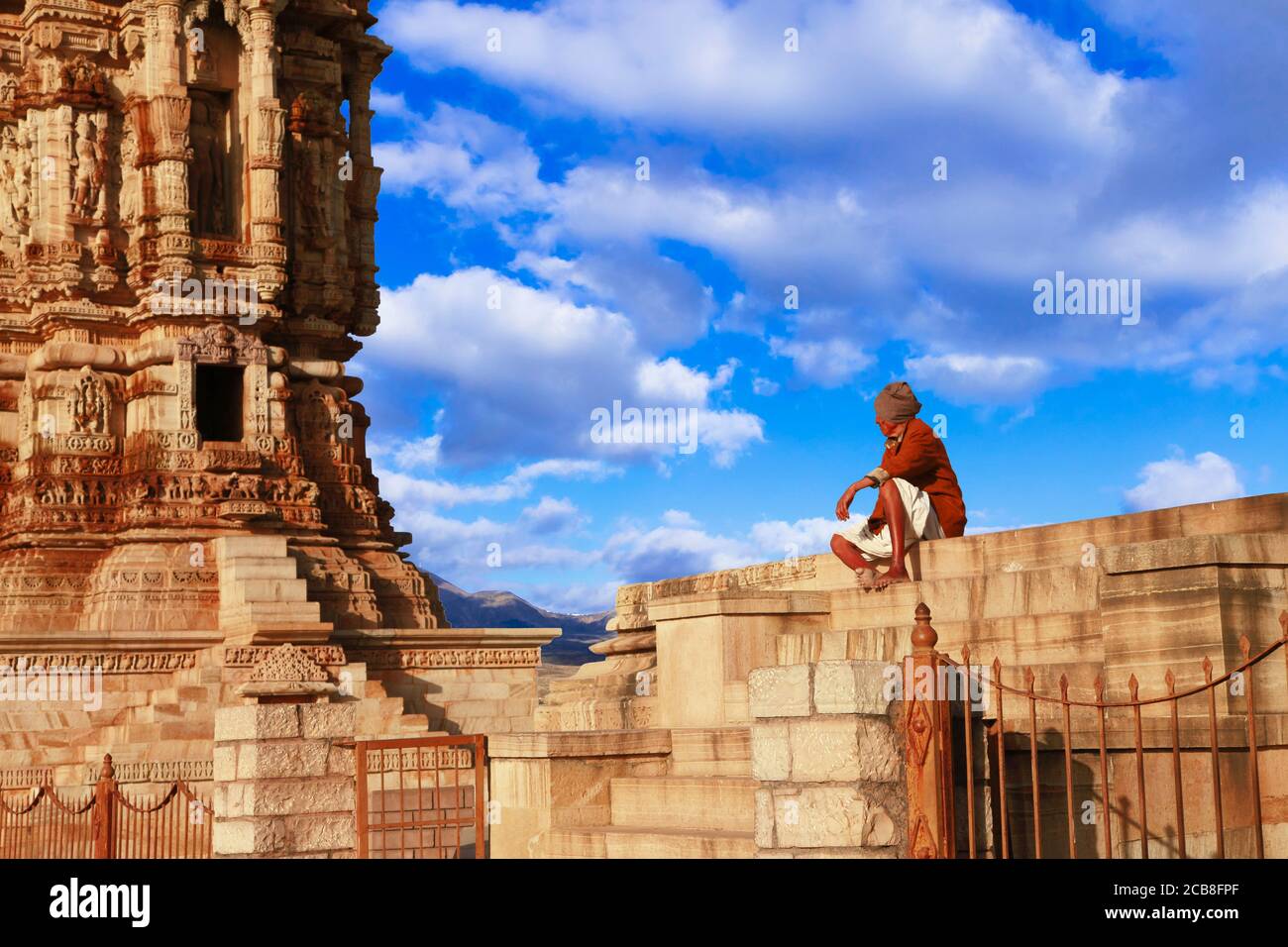 Incredibile India - forte Chittorgarh. Sito patrimonio dell'umanità dell'UNESCO. Famoso alto scolpito torre e vecchio uomo seduta nearby.Cittor città, Rajasthan, febbraio 2013 Foto Stock