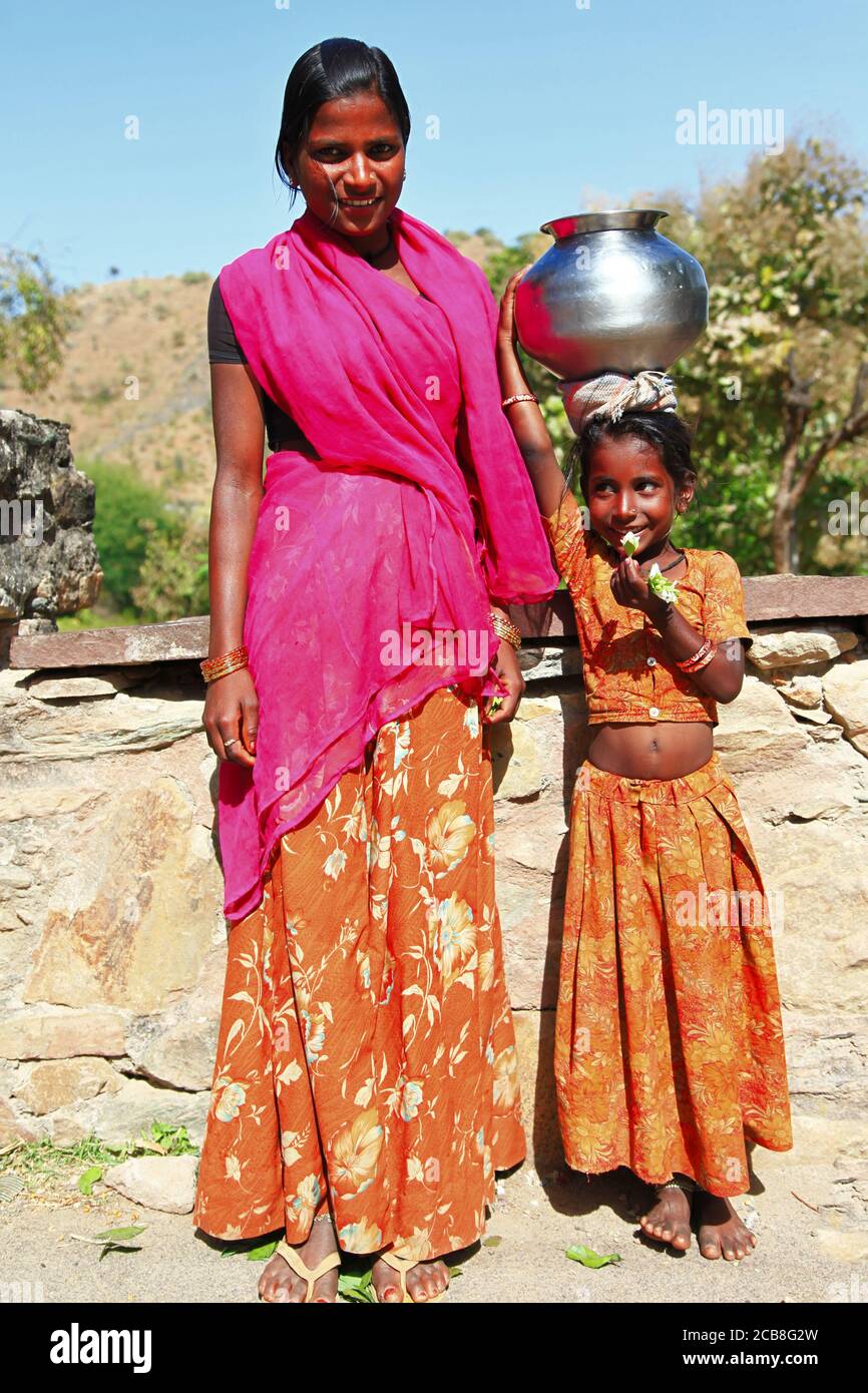 Affascinanti ragazze indiane dalla famiglia povera con pentola d'acqua tradizionale sulla testa. India, Rajasthan. feb 2013 Foto Stock