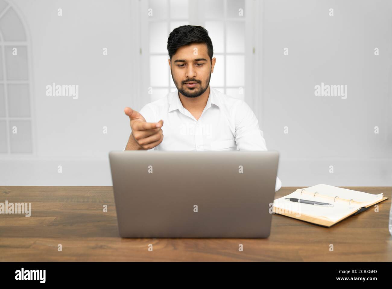 Giovane uomo d'affari indiano asiatico che lavora su un computer portatile in un ufficio moderno Foto Stock