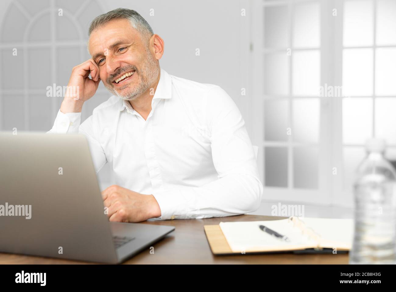 Imprenditore di successo lavorando su laptop nel lusso moderno, scrivania in ufficio. Il giovane imprenditore soddisfatto con il risultato di lavoro analizzando gli indicatori finanziari su Foto Stock